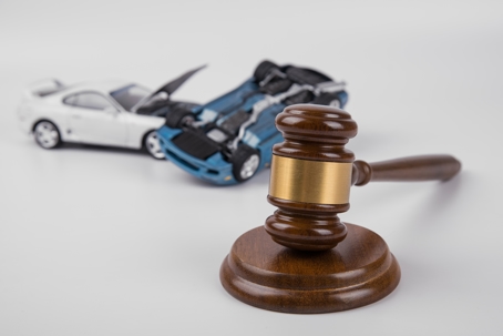 Legal gavel in white space with cars in the background