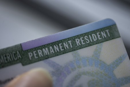 Close up view of Fragment of Permanent resident card (Green) card of USA on blurred background.
