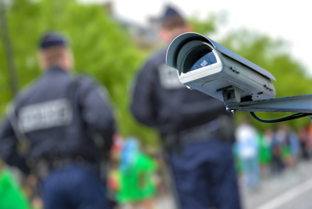 ocus on security CCTV camera or surveillance system with police officers on blurry background