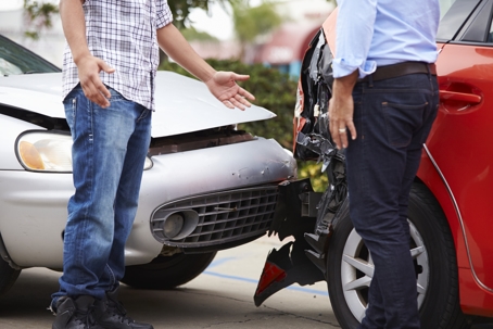 Two people arguing in front of a car crash